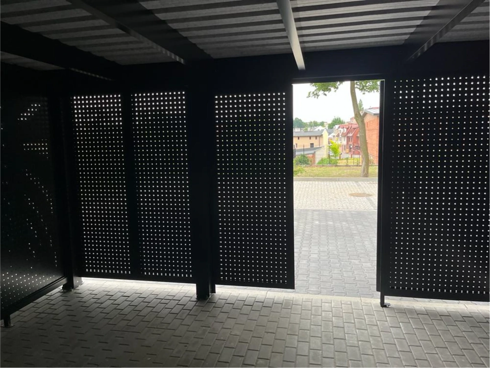 Wnętrze wiaty garażowej z perforowanymi panelami aluminiowymi i podjazdem z kostki