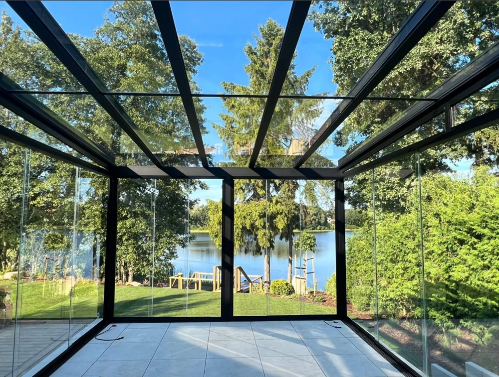 Przeszklone zadaszenie tarasowe z aluminiową konstrukcją, widok na ogród i jezioro