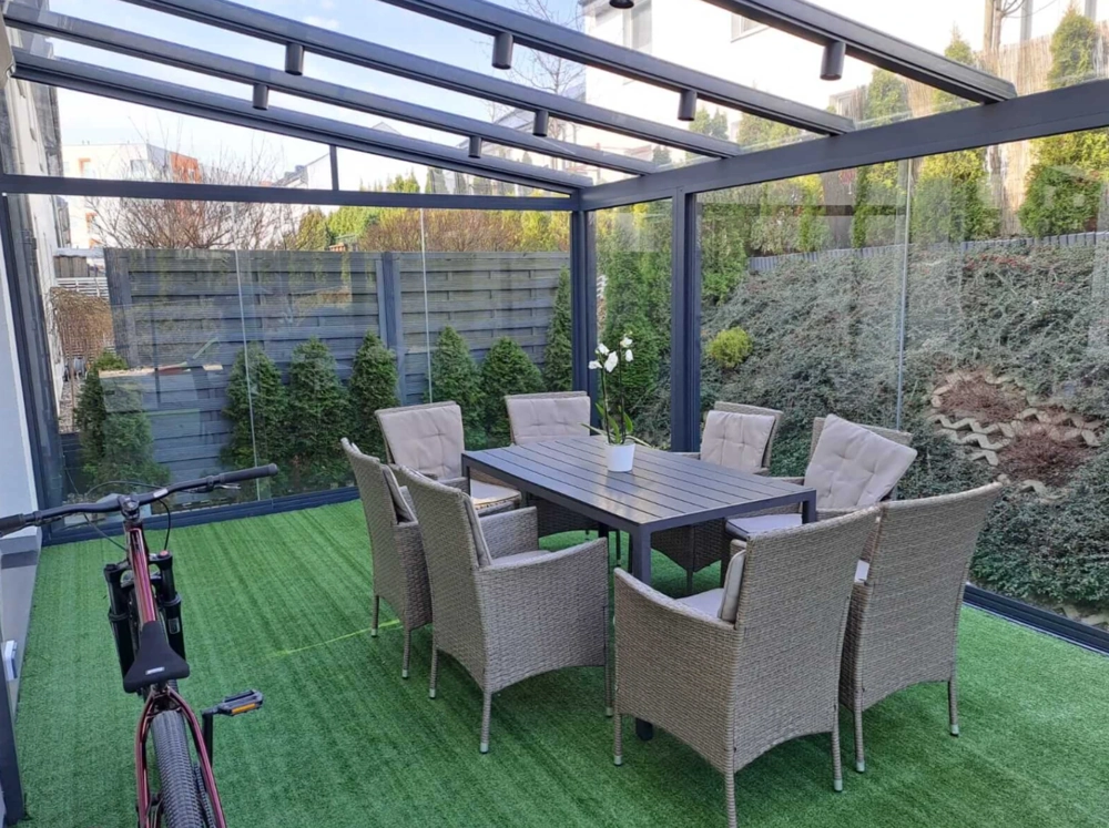 Zadaszenie tarasowe z aluminiową konstrukcją i przesuwnymi szklanymi ścianami nad jadalnią ogrodową