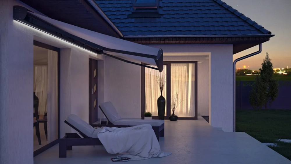 Markiza tarasowa nad nowoczesnym tarasem z leżankami i podświetlonym wejściem