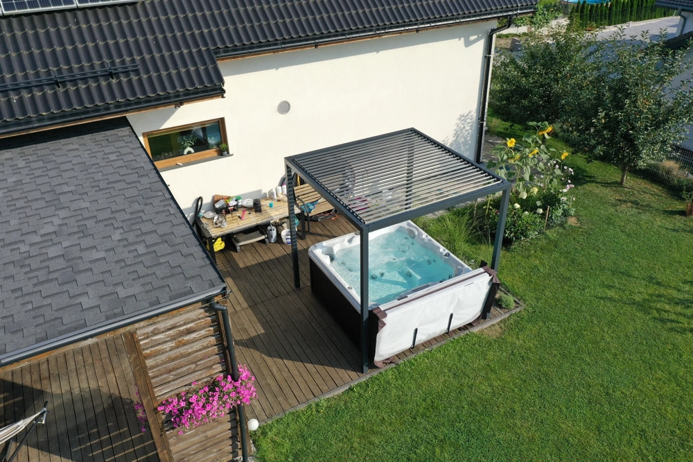 Jacuzzi na drewnianym tarasie pod aluminiowym zadaszeniem do spa z regulowanymi lamelami